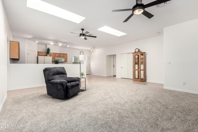 sitting room featuring ceiling fan, light carpet, a skylight, visible vents, and baseboards