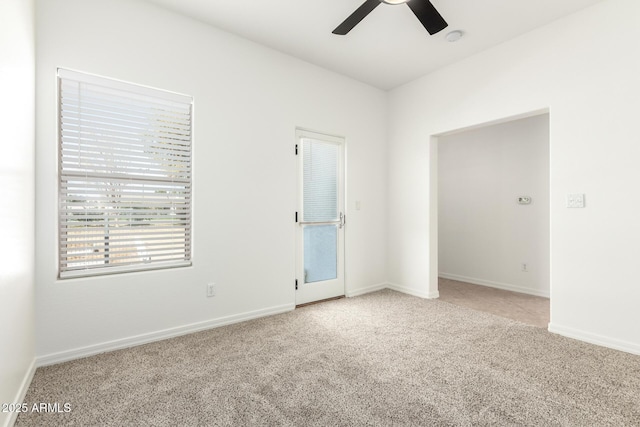 empty room featuring carpet flooring, a ceiling fan, and baseboards