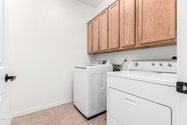 laundry area with washing machine and dryer, cabinet space, and baseboards