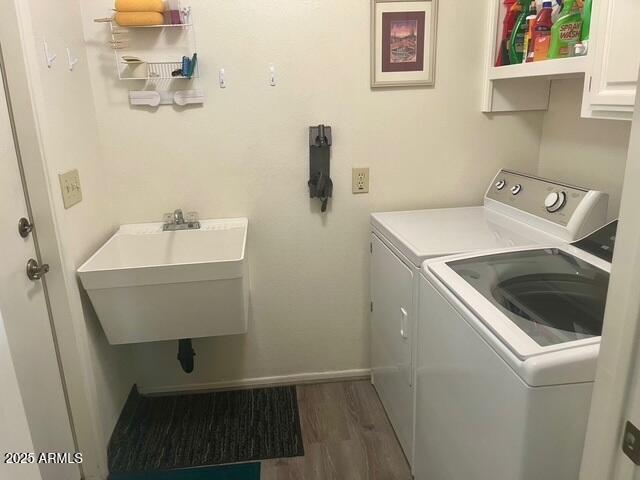 washroom featuring dark wood-style floors, baseboards, cabinet space, separate washer and dryer, and a sink