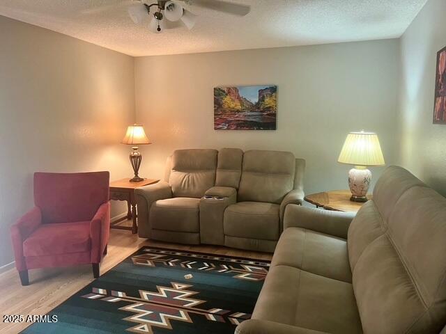 living room featuring light wood finished floors, a textured ceiling, and a ceiling fan