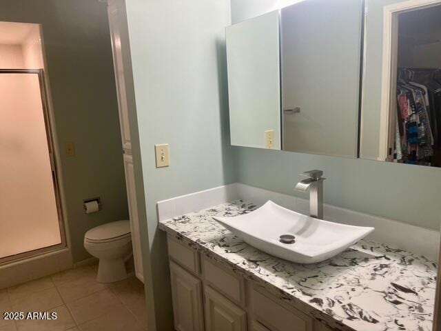 bathroom with tile patterned floors, toilet, a stall shower, and vanity