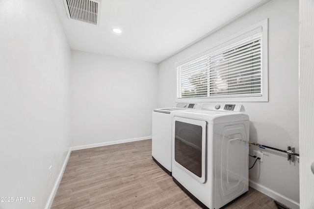 clothes washing area featuring washer and dryer and light hardwood / wood-style flooring