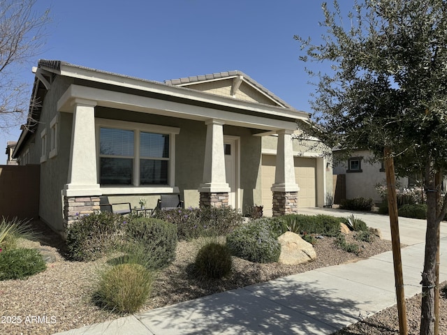 view of front facade with driveway, a garage, stone siding, covered porch, and stucco siding