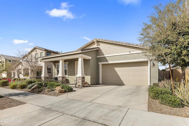 view of front of house with an attached garage, covered porch, driveway, stone siding, and stucco siding