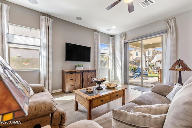 living area featuring visible vents, ceiling fan, baseboards, and wood finished floors