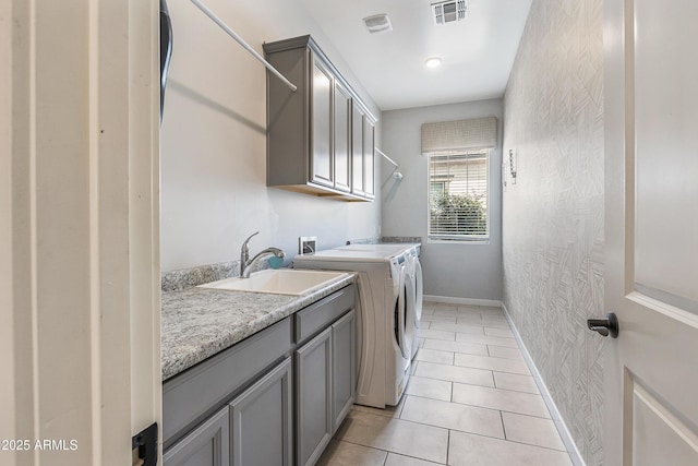 clothes washing area with visible vents, cabinet space, light tile patterned flooring, a sink, and washer and dryer