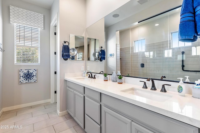 bathroom featuring a walk in shower, double vanity, a sink, and baseboards