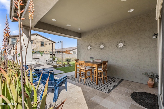 view of patio / terrace with outdoor dining area, fence, and a residential view