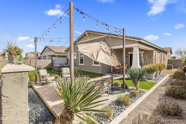 rear view of property featuring a patio area, fence, and stucco siding