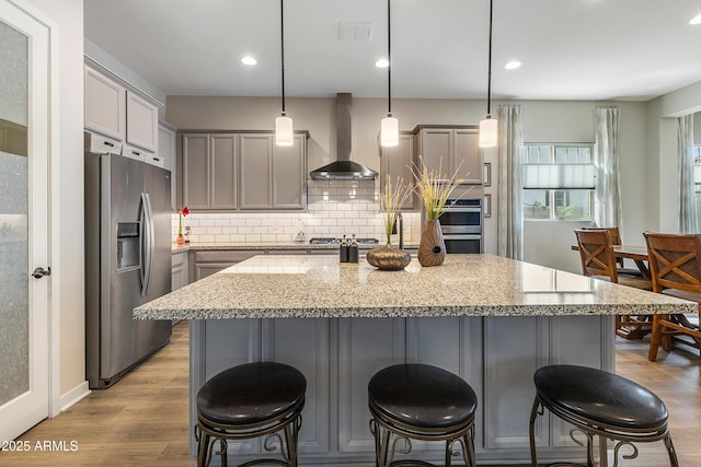 kitchen with gray cabinets, visible vents, light wood-style flooring, appliances with stainless steel finishes, and wall chimney exhaust hood