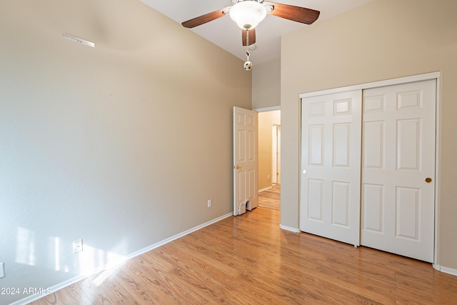 unfurnished bedroom with a high ceiling, a closet, light hardwood / wood-style flooring, and ceiling fan