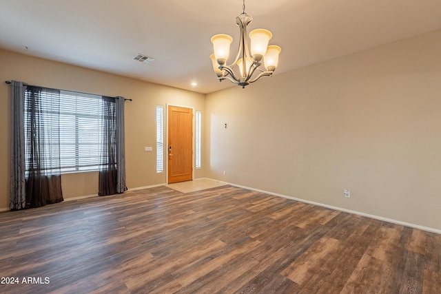 unfurnished room with dark hardwood / wood-style floors and an inviting chandelier