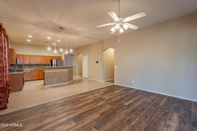 kitchen featuring a center island, ceiling fan, tasteful backsplash, light hardwood / wood-style floors, and stainless steel appliances