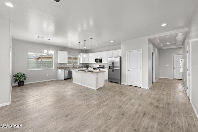 kitchen featuring stainless steel appliances, a center island, light hardwood / wood-style floors, white cabinets, and pendant lighting