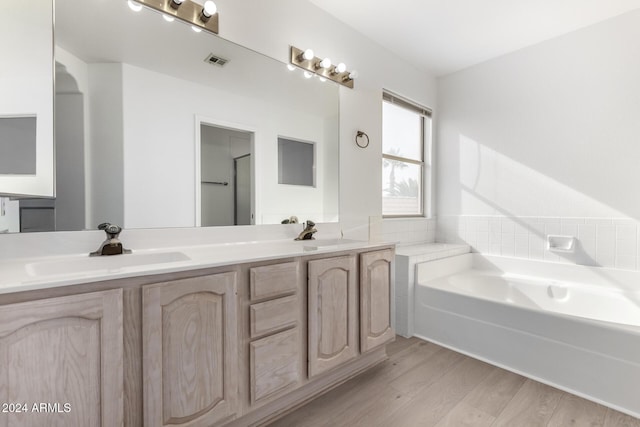 bathroom with hardwood / wood-style flooring, vanity, a bathing tub, and backsplash