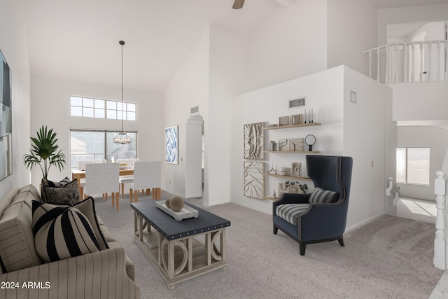 carpeted living room with plenty of natural light, high vaulted ceiling, and a chandelier