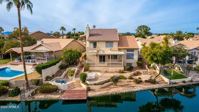 rear view of house with a fenced in pool, a patio area, a balcony, and a water view