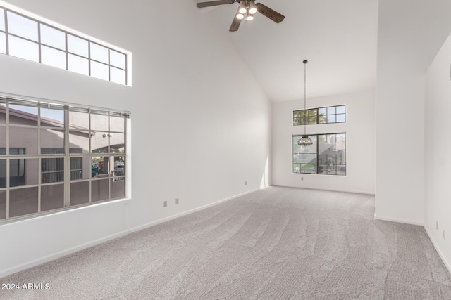 interior space with ceiling fan with notable chandelier, light colored carpet, and high vaulted ceiling