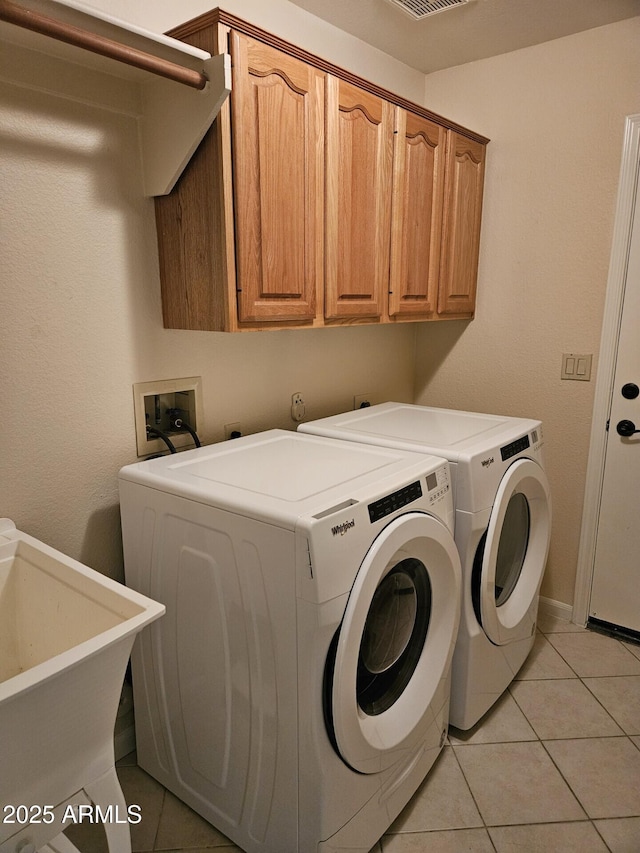 laundry area with visible vents, a sink, cabinet space, light tile patterned floors, and washing machine and clothes dryer