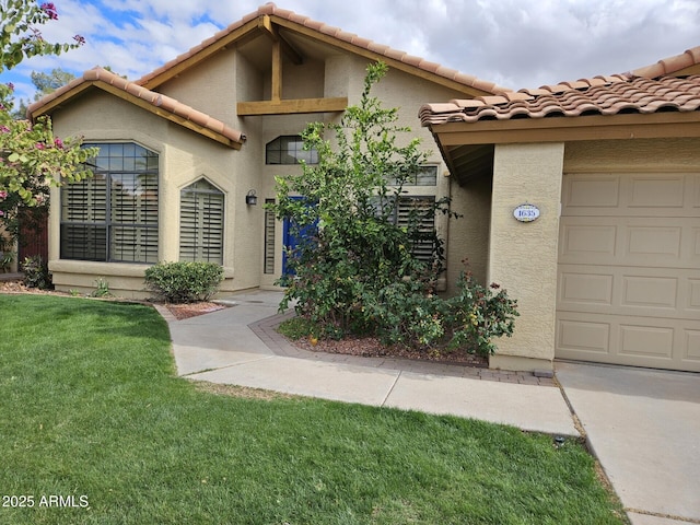 view of front of property with a front yard, a tiled roof, an attached garage, and stucco siding