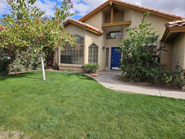 view of front of property with stucco siding, a tiled roof, and a front lawn