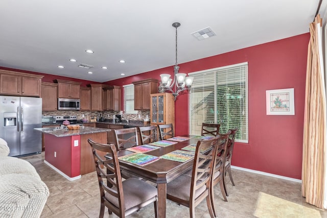 dining room with a chandelier, a wealth of natural light, and light tile patterned flooring