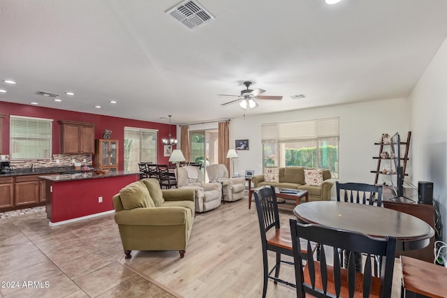 dining space with ceiling fan with notable chandelier, light hardwood / wood-style floors, and sink