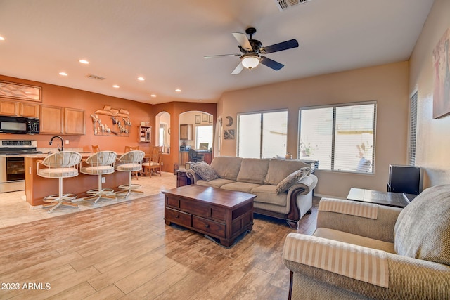 living room with ceiling fan, light wood-type flooring, and sink