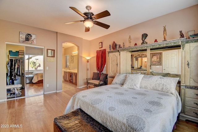 bedroom with ceiling fan, ensuite bath, wood-type flooring, and a closet