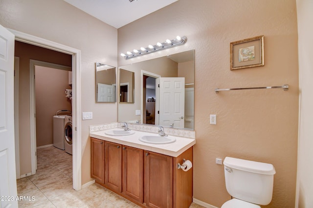 bathroom featuring toilet, vanity, tile patterned floors, and washing machine and dryer