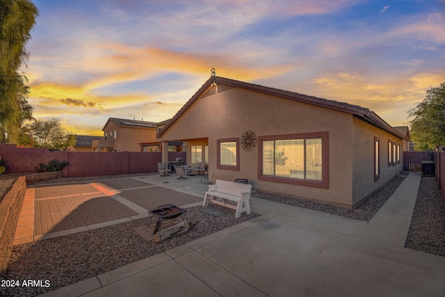 back house at dusk featuring a patio