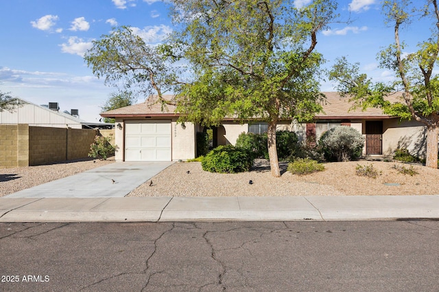 view of front of home with concrete driveway, an attached garage, fence, and stucco siding