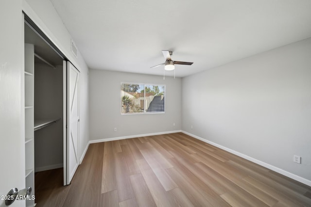 unfurnished bedroom featuring visible vents, a ceiling fan, wood finished floors, a closet, and baseboards