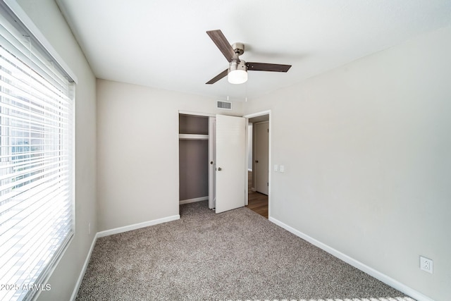 unfurnished bedroom with visible vents, multiple windows, baseboards, and carpet flooring