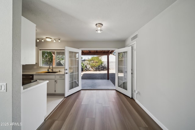 interior space featuring visible vents, light countertops, french doors, white cabinets, and a sink