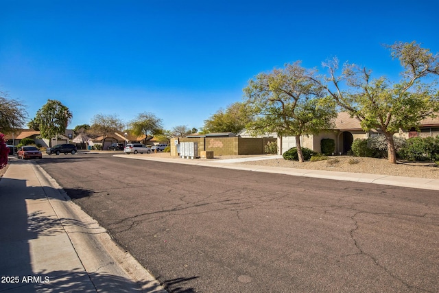 view of street featuring a gate, curbs, sidewalks, and a residential view