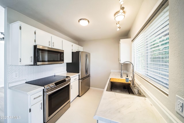 kitchen featuring tasteful backsplash, stainless steel appliances, light countertops, and a sink