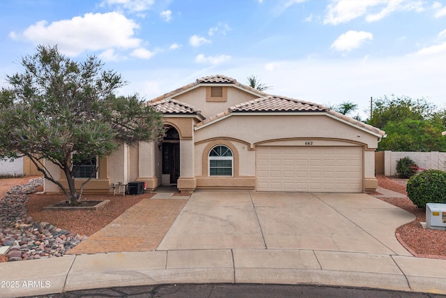 662 S Saddle St, Gilbert, AZ 85233 - mediterranean / spanish house featuring an attached garage, concrete driveway, a tiled roof, stucco siding, and fence