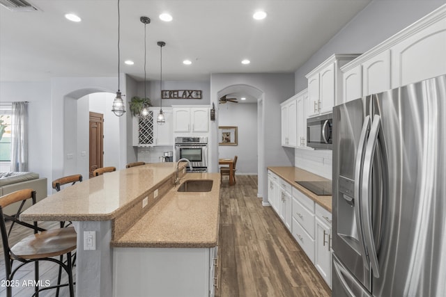 kitchen with pendant lighting, white cabinetry, stainless steel appliances, sink, and a breakfast bar