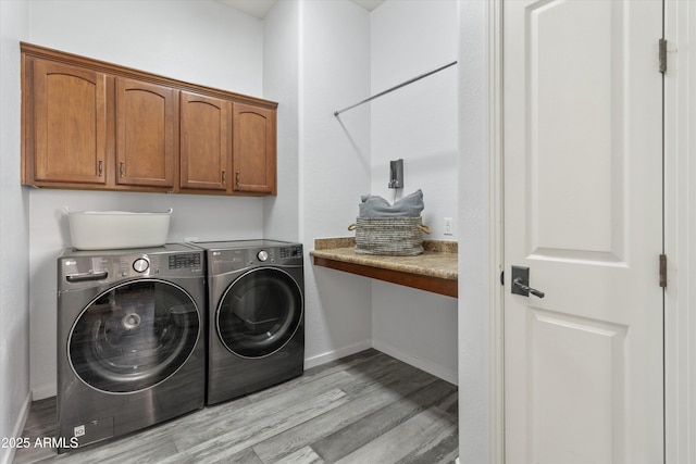 clothes washing area featuring light hardwood / wood-style flooring, cabinets, and washer and dryer