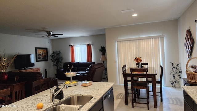 kitchen with light tile patterned floors, light stone counters, and ceiling fan