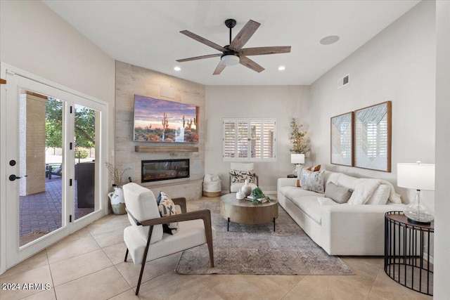 living room featuring ceiling fan, light tile patterned flooring, and a tile fireplace