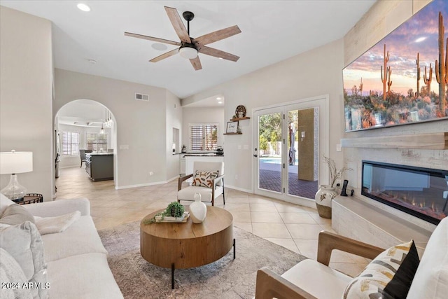 living room with a premium fireplace, ceiling fan, light tile patterned flooring, and french doors