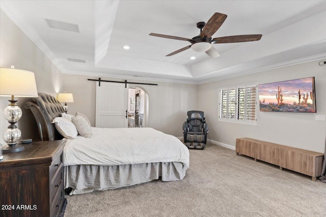 carpeted bedroom with ceiling fan, a tray ceiling, crown molding, and a barn door