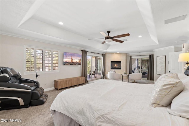 bedroom with ceiling fan, radiator heating unit, a tray ceiling, light colored carpet, and access to exterior