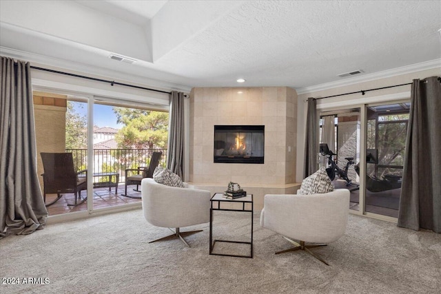 living room with a textured ceiling, ornamental molding, carpet flooring, and a fireplace