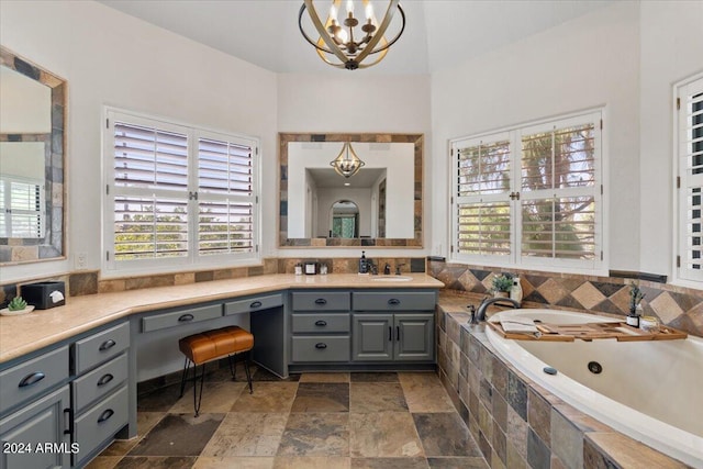 bathroom with a chandelier, tiled bath, and vanity