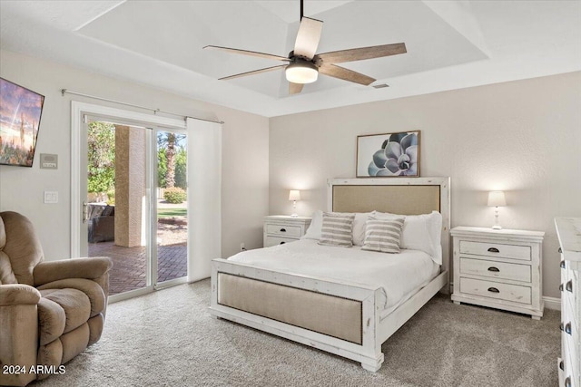 carpeted bedroom with access to outside, a tray ceiling, and ceiling fan