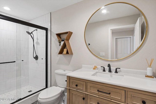 bathroom with vanity, toilet, and a shower with door